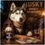 Husky dog in a brown scarf and coat seated at a wooden table with a can of Howl & Roast, newspaper, sharpened pencils, and mugs from Huskville Brewery under a sign that reads Husky Smoky Snowdogs.