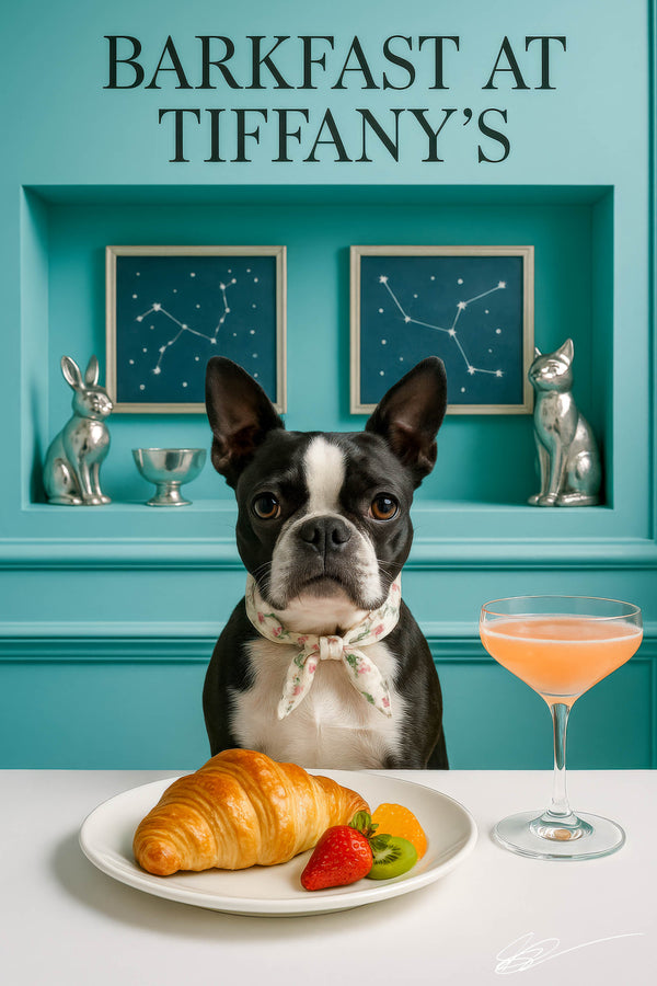 Tuxedo-masked Boston Terrier in a floral scarf at white table with croissant, strawberry, kiwi slice & blush cocktail under neon “Barkfast at Tiffany’s” sign