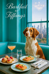 Brittany Spaniel on a turquoise banquette by a city-view window with plates of strawberry-topped profiteroles, smoked-salmon & cucumber toasts, a peach-hued cocktail and glass of water under “Barkfast at Tiffany’s” script