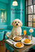 Cavachon dog sitting in a turquoise café booth at Barkfast at Tiffany’s with plates of fig-topped toast, mini quiches, a mimosa, and a white flower on a round table