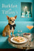 Chihuahua in black bowtie seated on turquoise banquette next to metal table with finger sandwiches, berries, water, cocktail and gift boxes