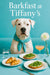 Dogo Argentino wearing turquoise scarf seated at turquoise booth with cheese-topped croissants, arugula toasts, glass of water, frothy cocktail, and white flower in vase
