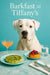 Dogo Argentino seated against a turquoise backdrop beside marble table with spinach frittata fruit pastry cocktail and glass of water