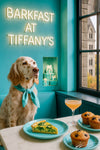 English setter wearing turquoise scarf sitting on turquoise banquette beside marble table with spinach quiche blueberry muffins and peach cocktail under neon Barkfast at Tiffany’s sign