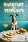 Italian Greyhound wearing cream scarf seated on teal banquette beside crostini with whipped cheese chives, golden muffins, pink cocktail and water glass