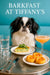 Black and white Japanese Chin on a teal banquette beside a metal table with spinach quiche topped with arugula apricot swirl pastries a pink cocktail and a water glass