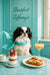Japanese Chin wearing a teal scarf seated at a marble table with a jar of granola yogurt parfait, avocado chicken toast, espresso, and a pink cocktail