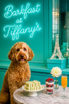 Apricot labradoodle seated before marble table with cucumber finger sandwiches berry parfait mimosa neon Barkfast at Tiffanys sign and crystal Eiffel Tower