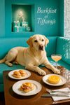Golden Labrador Retriever lounging on turquoise banquette at wooden café table with ham croissants orange tart and peach cocktail under Barkfast at Tiffanys sign and turquoise gift boxes