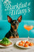 Black-and-tan Miniature Pinscher wearing a silver chain seated at a turquoise banquette with avocado toast topped with arugula, smoked salmon canapé rounds with crème fraîche, and a peach cocktail under a Barkfast at Tiffany’s sign