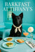 Black Mudi wearing an ivory scarf seated at a turquoise café table with spinach quiches, apple-topped toast, peach cocktail, and white dahlia under Barkfast at Tiffany’s sign