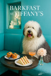 Fluffy Old English Sheepdog seated on a teal banquette beside a dark marble café table with blueberry muffins shrimp tea sandwiches a pink cocktail and a pale pink peony