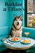 Alaskan Malamute wearing a Tiffany-blue scarf seated at a café table with shrimp canapés, melon cubes, and a peach cocktail by a window
