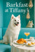 American Eskimo Dog seated at a Tiffany-blue café table with croissants, potato quiches, a coffee cup and a peach cocktail beneath sparkling chandeliers