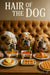 Three bulldogs at a table with pancakes, waffles, croissant, dog biscuits, and drinks under a “Hair of the Dog” sign