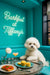 Fluffy Bichon Frise leaning on a Tiffany-blue banquette table with tomato toast, lemon muffins, a peach cocktail, glasses of water, and a white flower vase