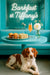 Brittany Spaniel lying under a turquoise table in a Tiffany-blue café, eyeing finger sandwiches, mini muffins, a peach-hued cocktail and white flower under neon “Barkfast at Tiffany’s” sign