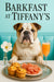 English Bulldog seated at a Tiffany-blue banquette with a silver tray holding three cheese muffins, a plate of thinly sliced prosciutto, a peach-hued cocktail and a white flower in a vase under “Barkfast at Tiffany’s” sign
