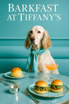 English setter wearing turquoise scarf seated on tufted turquoise banquette beside round table with arugula sliders plain brioche bun frothy cocktail and silver sugar bowl
