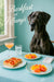 Great Dane at turquoise café table with tomato focaccia citrus fruit plates cocktail water glass and napkin by window