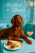 Auburn Irish Setter reclining on teal banquette beside plate of bacon lettuce sliders lemon tarts and a pink cocktail