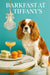 Ruby and white King Charles Cavalier seated on a teal ottoman beside cucumber tea sandwiches, golden muffins, and a peach cocktail under a crystal pendant
