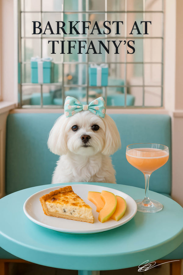 White Maltese wearing a floral bow seated at a turquoise café table with a slice of spinach quiche cantaloupe wedges and a peach cocktail under Barkfast at Tiffanys sign