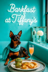 Black and tan Miniature Pinscher wearing a turquoise scarf on a matching banquette beside a tray of spinach muffins swirl pastry apple danish and a peach mimosa under a Barkfast at Tiffanys sign