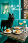 Black Mudi standing on a turquoise banquette behind a metal table with a golden muffin, avocado and smoked salmon toast, egg salad toast, peach cocktail, and white dahlia under a Barkfast at Tiffany’s sign
