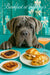 Grey Neapolitan Mastiff leaning over a turquoise café table with croissant sandwiches, berry jam toast and a peach cocktail under Barkfast at Tiffany’s sign