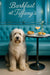 Fluffy Old English Sheepdog seated on a teal banquette beside a round marble table with a golden pastry ring two mini quiches a pink cocktail and white flowers