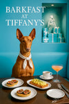 Pharaoh Hound seated on a teal banquette beside a dark wood café table with two fig tartlets scrambled eggs toast a coffee cup and a pink spritz