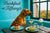 Rhodesian Ridgeback seated on a turquoise banquette beside a large window overlooking autumn foliage in a chic café setting