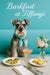 Whiskered Schnauzer wearing a turquoise scarf seated on a teal café banquette beside a vase of pastel flowers