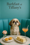 Shih Tzu seated on a turquoise banquette beside a marble table with two peach tartlets stacks of crustless tea sandwiches a pink cocktail with striped straw and a single pink blossom in a vase