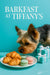 Yorkshire terrier sniffing a plate of mini croissants and pastel macarons next to Tiffany blue gift boxes on a teal table